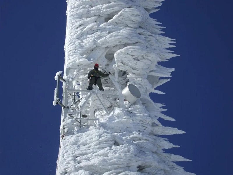 A communication tower covered in ice after a snowstorm.